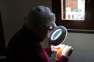 Senior woman looking through magnifying glass