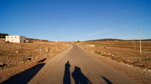 Shadow of man on road against clear sky