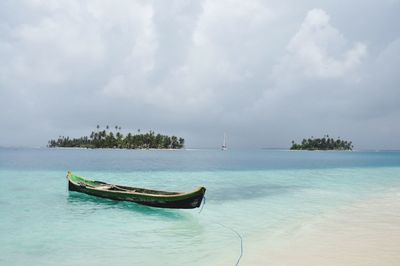 Boats in sea against cloudy sky