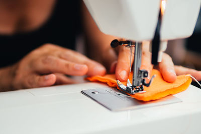 Cropped hands of woman using sewing machine at workshop