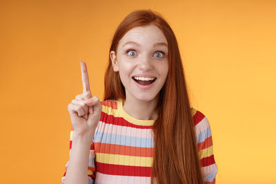 Portrait of smiling young woman against gray background