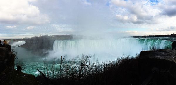 Scenic view of waterfall against cloudy sky