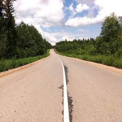 Road by trees against sky