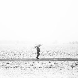 Man on beach against clear sky during winter