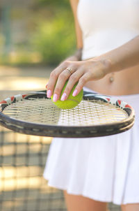 Midsection of woman holding tennis