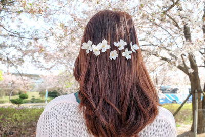 Rear view of woman wearing flowers in hair at park