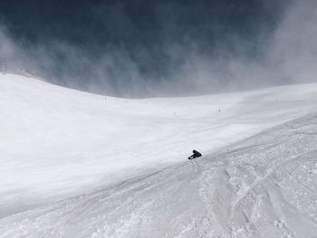 Low angle view of person on snowcapped mountain against sky