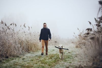 Full length of man with dog standing on field