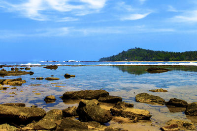 Rocks on shore by sea against sky