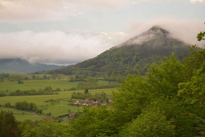 Scenic view of green landscape and mountains against sky