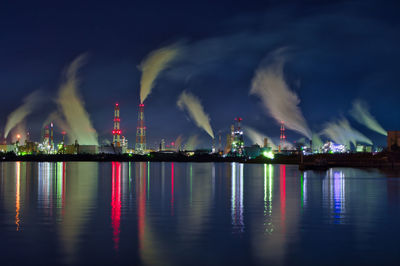 Panoramic view of illuminated factory against sky at night