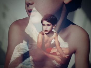 Double exposure of shirtless boy sitting outdoors