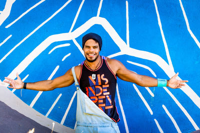 Portrait of young man with arms outstretched