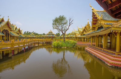 Panoramic view of temple by lake and buildings against sky