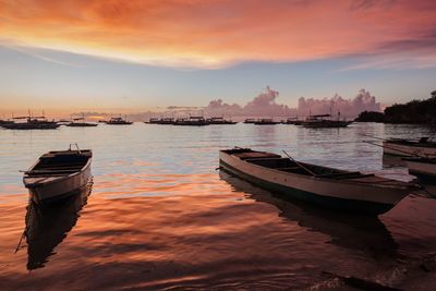 Boats moored on sea against sky during sunset