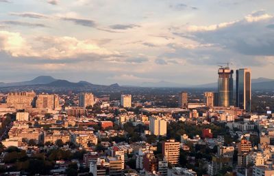 High angle view of city buildings against cloudy sky