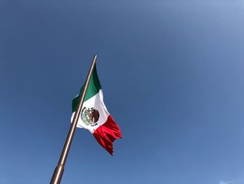 Low angle view of flag flags against clear blue sky