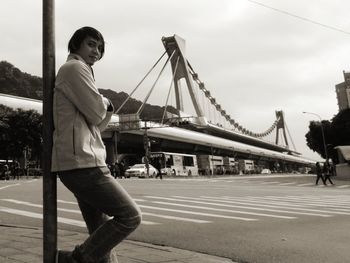Man on bridge against sky in city