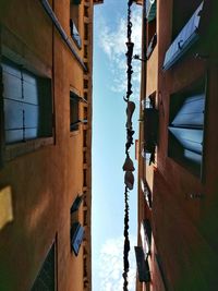 Low angle view of cross hanging in city against sky