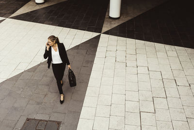 High angle view of businesswoman talking through phone while walking on street