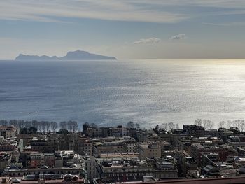 High angle view of townscape by sea against sky during sunset