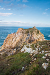 Rocks on shore by sea against sky