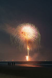 Firework display over sea against sky at night