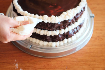 Cropped image of hand by cake on table