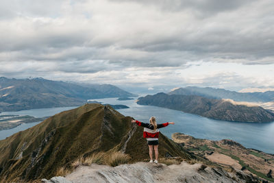 Rear view of woman standing on mountain against sky