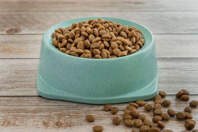 Dry food for cats and dogs in a green bowl on a wooden background. side viev.