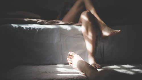 Low section of woman relaxing on bed