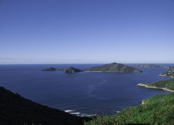 Scenic view of sea and mountains against clear blue sky