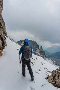 Rear view of man walking on snow covered mountain