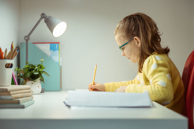 Cute girl writing on book in office