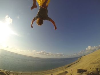 Low angle view of man jumping on landscape against sky
