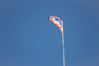 Low angle view of flag against clear blue sky