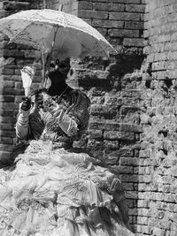 Midsection of woman with umbrella on cobblestone