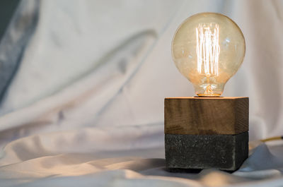 Close-up of illuminated light bulb on table