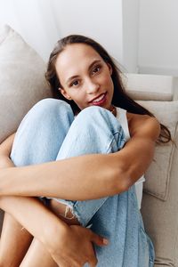 Portrait of young woman sitting on sofa at home