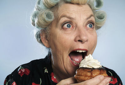 Portrait of senior woman with hair curlers eating sweet food