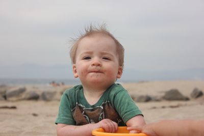 Portrait of cute boy at beach against sky