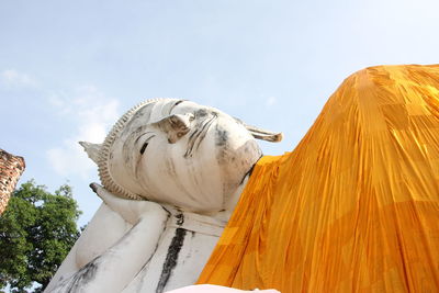 Low angle view of reclining buddha statue against sky