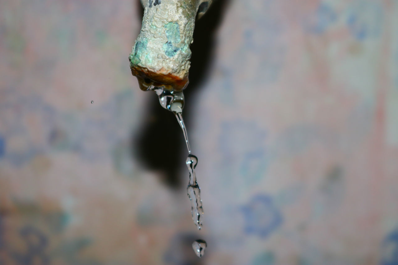 CLOSE-UP OF WATER DROP FALLING FROM FAUCET IN CONTAINER