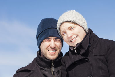 Portrait of smiling couple standing against sky during winter