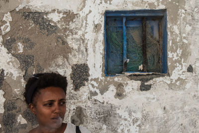 Portrait of young man looking through window in old building