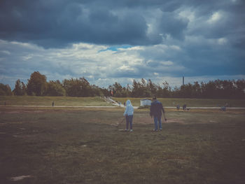 Rear view of men on field against sky