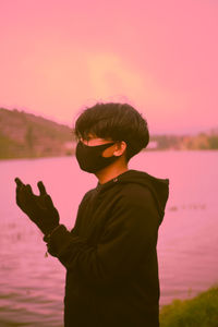 Man standing by lake against sky during sunset