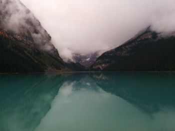 Scenic view of lake and mountains during foggy weather