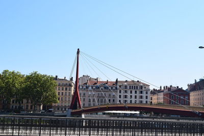 Bridge over buildings in city against clear sky