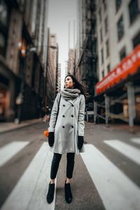 Full length of young woman standing on city street